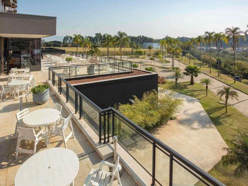 a balcony with tables and chairs and palm trees at ibis Styles Taubate in Taubaté