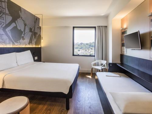 a hotel room with two beds and a window at ibis Styles Taubate in Taubaté
