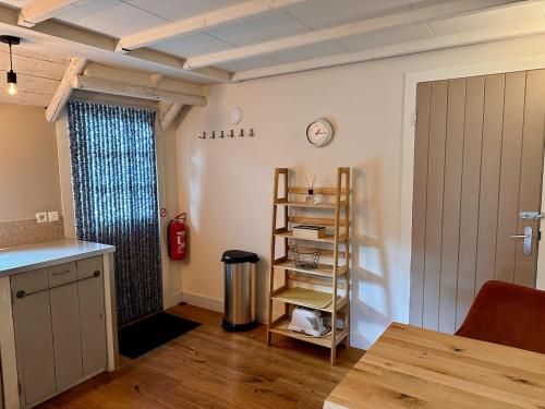 a kitchen with a shelf and a clock on the wall at B&B Woudzicht in Oudeschoot