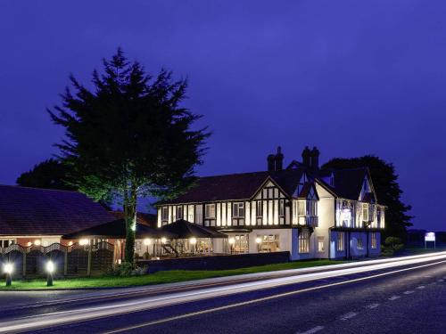 a large house with lights on a street at night at Mercure Thame Lambert Hotel in Chinnor