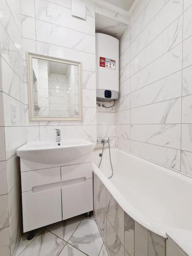 a white bathroom with a sink and a bath tub at 17-Avenue Apartment in Chernivtsi