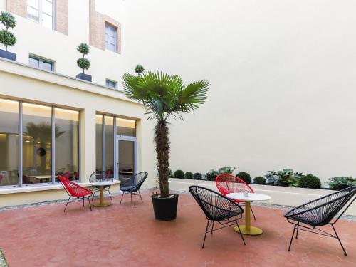 a group of chairs and tables and a palm tree at Ibis Styles Toulouse Capitole in Toulouse
