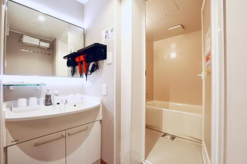 a bathroom with a sink and a mirror and a tub at Hotel 88 Shinsaibashi in Osaka