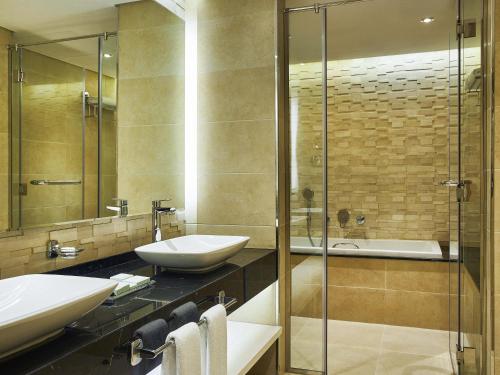 a bathroom with a sink and a glass shower at Mercure Dubai Barsha Heights Hotel Suites And Apartments in Dubai