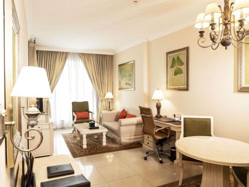 a living room with a couch and a desk in a room at Mercure Dubai Barsha Heights Hotel Suites And Apartments in Dubai