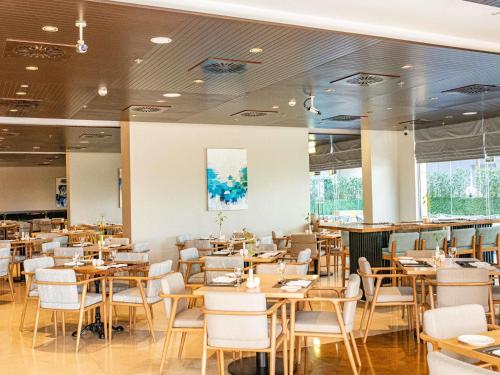 a restaurant with wooden tables and white chairs at Mercure Dubai Barsha Heights Hotel Suites And Apartments in Dubai