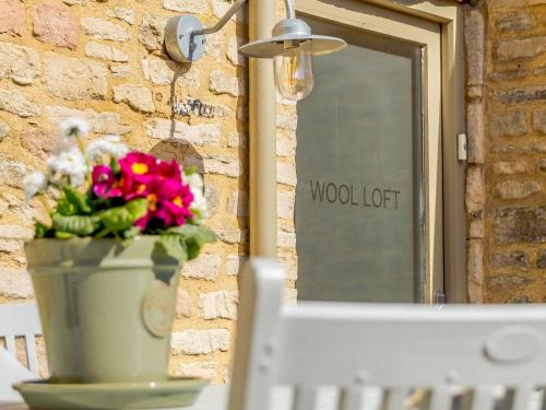 a pot of flowers on a table in front of a window at Wool Loft in Kemble