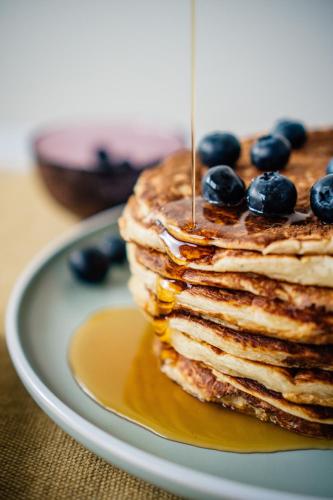 a stack of pancakes with blueberries and syrup on a plate at First Hotel Millennium in Oslo