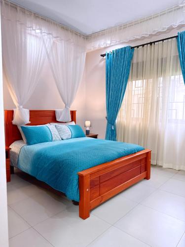 a bedroom with a bed with blue sheets and curtains at Jay Jay Homes in Kampala