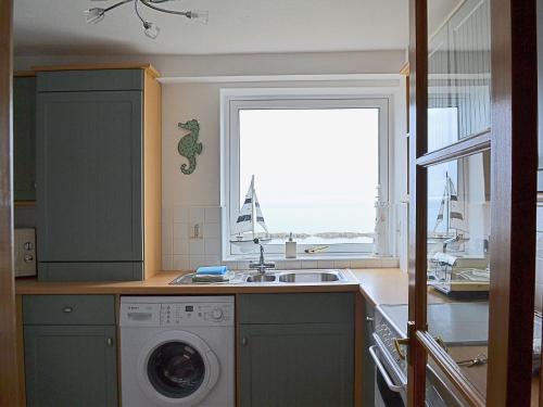 a kitchen with a sink and a washing machine at Making Waves in Anstruther