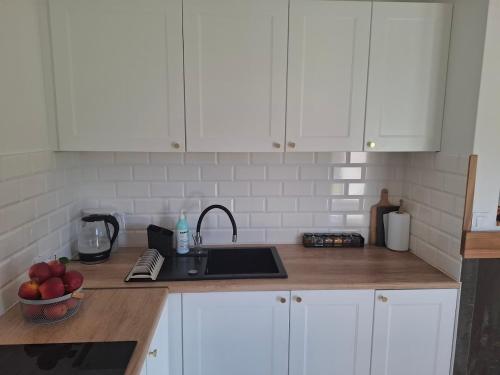 a kitchen with white cabinets and a sink and apples on the counter at Domek wśród Jabłonek in Łoniów