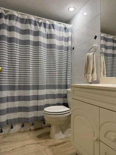 a bathroom with a toilet and a shower curtain at MAITENCILLO VISTA BOSQUE y MAR in Maitencillo
