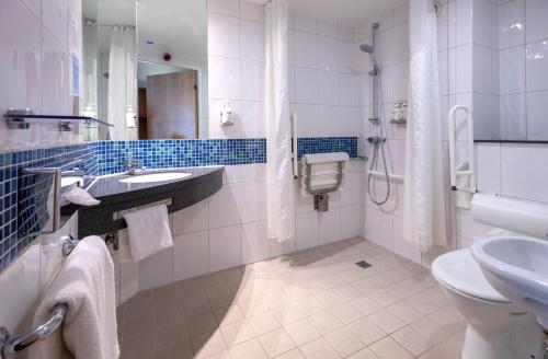 a bathroom with a toilet and a sink and a shower at Holiday Inn Express Bedford by IHG in Bedford