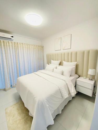 a white bedroom with a large bed with white sheets at Pure Bliss Ocean Apartment in Kingsborough