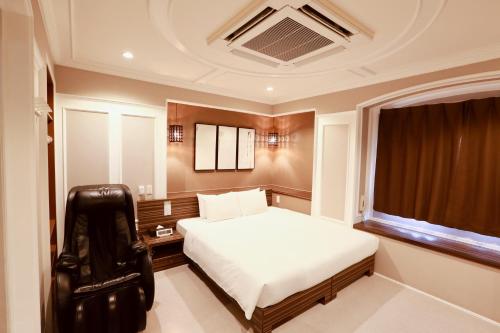 a bedroom with a white bed and a black chair at Hotel 88 Shinsaibashi in Osaka