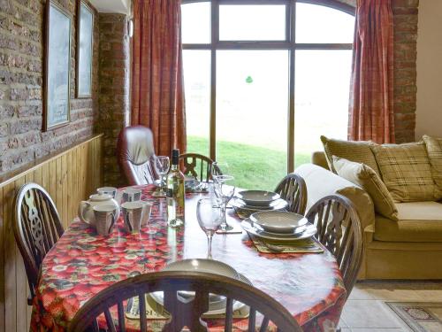 a dining room with a table with chairs and a window at Nightingale Cottage- 25115 in Flamborough