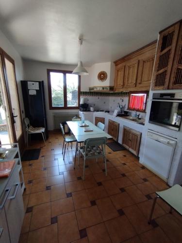 a kitchen with a table and a white refrigerator at Maison de vacances avec piscine et jardin in Bompas