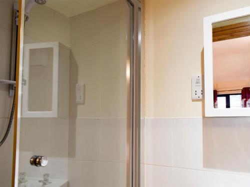 a shower with a glass door in a bathroom at Ty Bach Twt in Llangeitho
