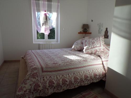 a bedroom with a bed with a blanket and a window at La Grange in Dieulivol