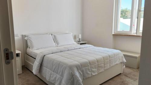 a white bed in a white bedroom with a window at Villa Incanto Pina - Torre Canne in Torre Canne