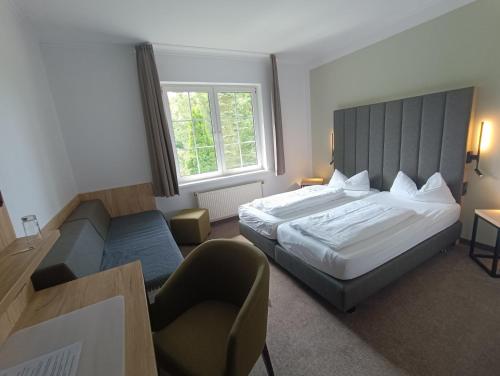 a hotel room with a bed and a chair at Gasthaus & Hotel Grünhof in Frankfurt Oder