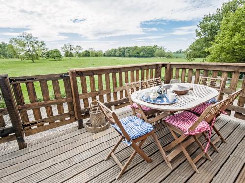 a wooden deck with a table and chairs on it at The West Barn in Hanley Castle