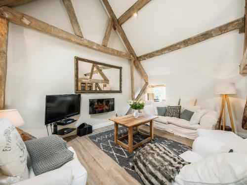 a living room with white furniture and a flat screen tv at The West Barn in Hanley Castle