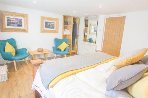 a bedroom with two blue chairs and a bed at Doolittle in Porthleven