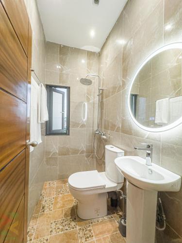 a bathroom with a toilet and a sink and a mirror at La Source, Kribi in Kribi