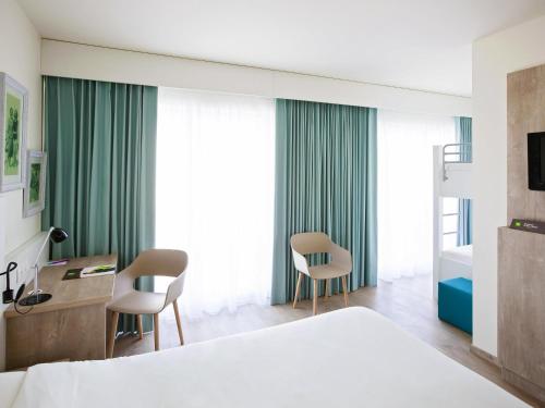a bedroom with a bed and a desk and chairs at ibis Styles Nieuwpoort in Nieuwpoort