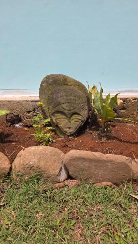 a statue of a head on the ground with rocks at La Maison de l'Artiste in Hauru