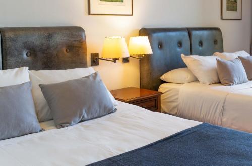 a hotel room with two beds and a table with two lamps at Wyndham Garden Luján in Luján