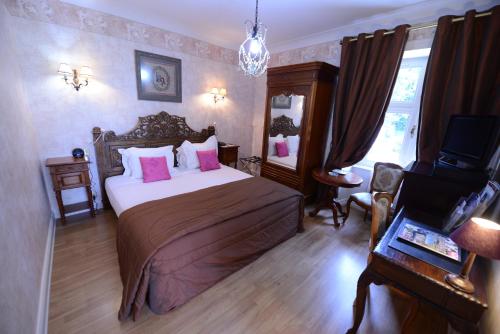 a bedroom with a large bed with pink pillows at Cit'Hotel Le Relais du Boisniard in Chambretaud