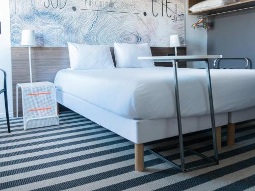 a bedroom with a white bed and a table at ibis Styles Perpignan Canet En Roussillon in Canet-en-Roussillon