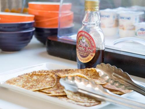 a plate of pancakes on a table with a bottle of syrup at ibis Styles Perpignan Canet En Roussillon in Canet-en-Roussillon