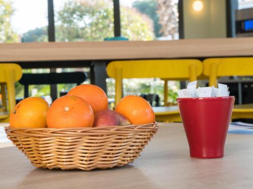 a basket of fruit on a table with a red cup at ibis Styles Perpignan Canet En Roussillon in Canet-en-Roussillon
