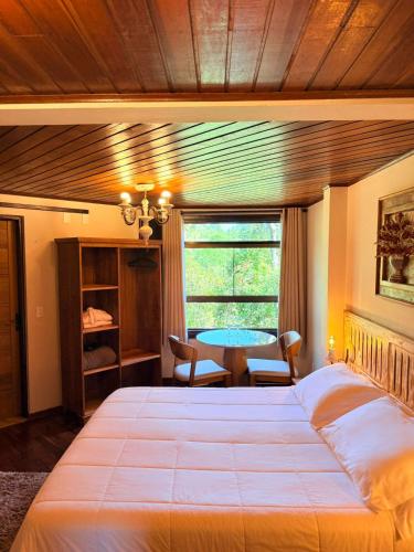 a bedroom with a large bed and a table at Pousada Cerejeiras in Monte Verde