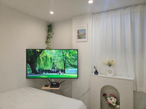 a bedroom with a flat screen tv on a wall at 오픈특가-역삼역7분,강남세브란스병원,코엑스,롯데월드,국립중앙박물관,홍대,명동,넷플릭스 in Seoul