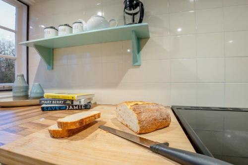 een brood op een snijplank met een mes bij Boldshaves Cottage in Woodchurch