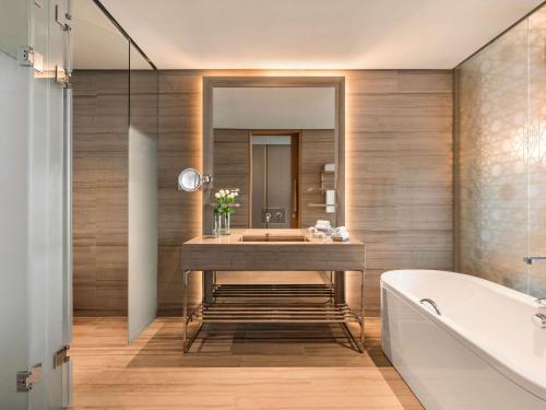 a bathroom with a sink and a tub and a mirror at Rixos Premium Dubai JBR in Dubai