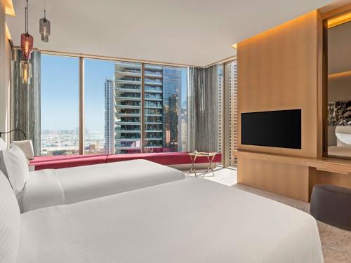 a hotel room with two beds and a flat screen tv at Rixos Premium Dubai JBR in Dubai