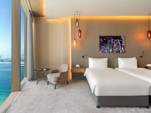 a hotel room with two beds and a chair at Rixos Premium Dubai JBR in Dubai