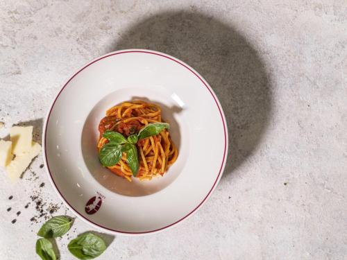 a plate of spaghetti with basil on a table at Rixos Premium Dubai JBR in Dubai