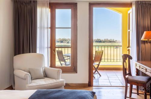 a room with a bed and a chair and a balcony at Wyndham Garden Luján in Luján