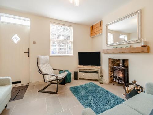 un soggiorno con divano, sedia e TV di Cherry Blossom Cottage a Etton