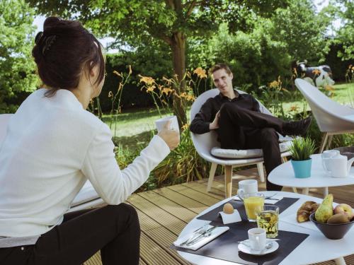 a woman sitting at a table with a man sitting in chairs at Mercure Lyon Genas Eurexpo in Genas