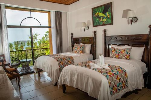 two beds in a room with a window at Hotel San Bada Resort & Spa in Manuel Antonio