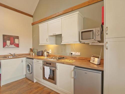 a kitchen with white cabinets and a microwave at Timberway in Okehampton