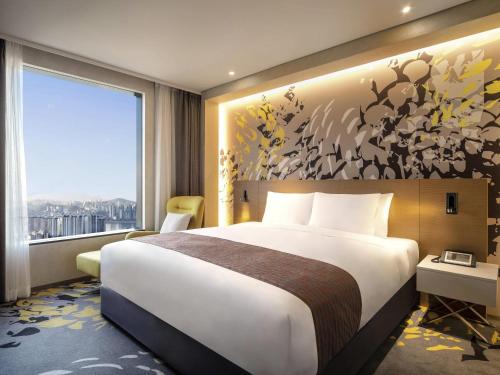 a hotel room with a bed and a large window at Novotel Suites Ambassador Seoul Yongsan in Seoul