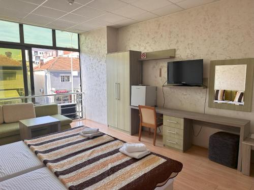 a room with a bed and a desk with a tv at Hotel Green Center Gili in Gostivar